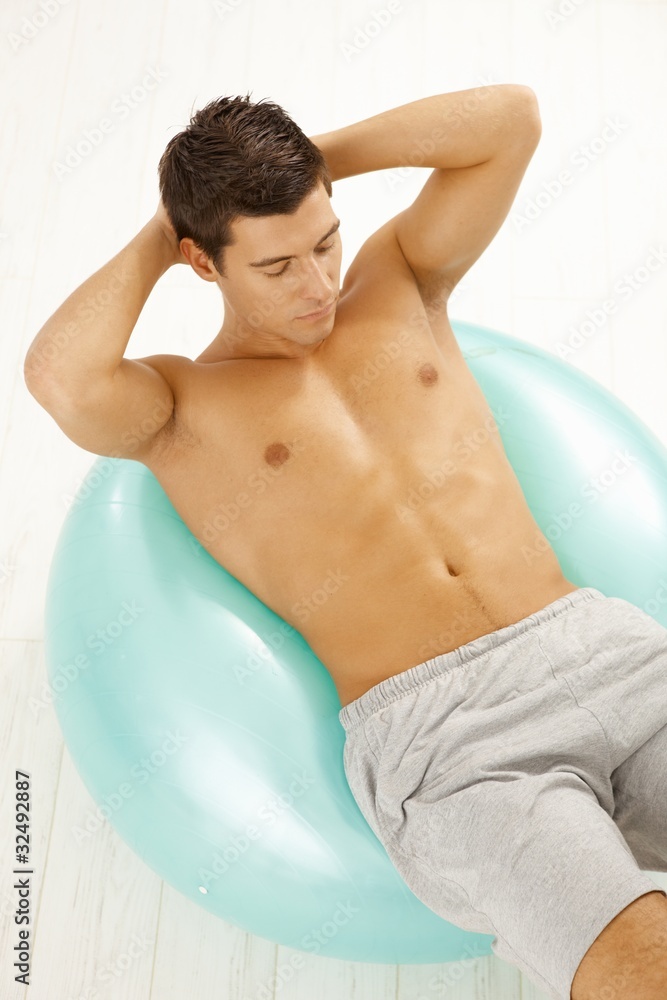 Sporty young man exercising on fit ball Sporty young man exercising on fit ball