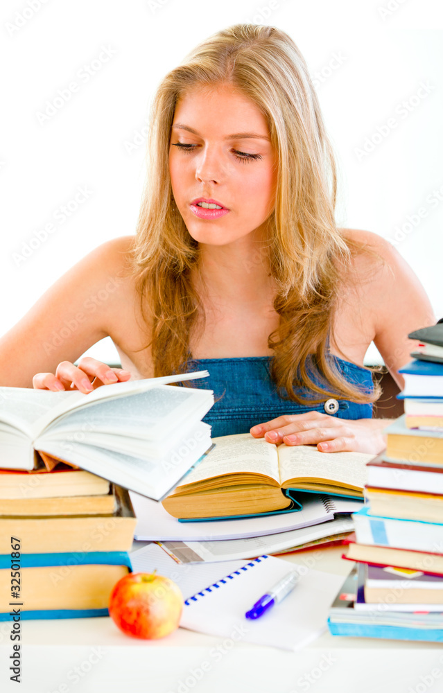 Concentrated teengirl sitting at table and searching in books. Concentrated teengirl sitting at table and searching in books.