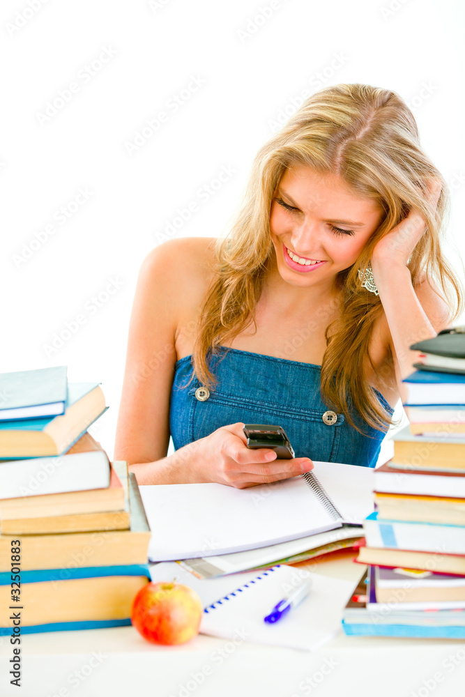 Smiling girl reading sms on mobile instead of doing homework. Smiling girl reading sms on mobile instead of doing homework.