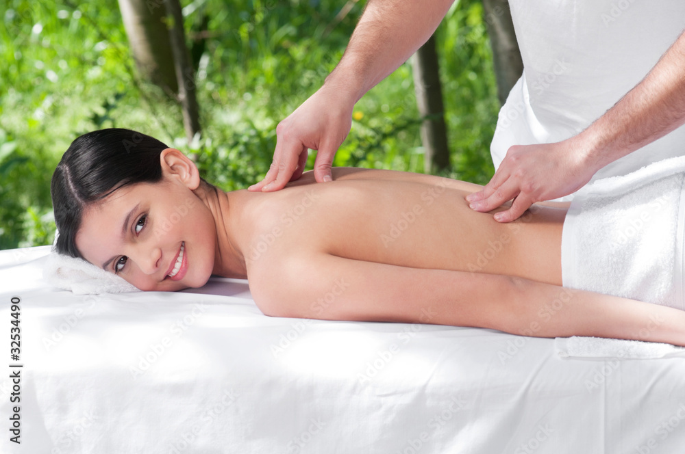 Happy young woman getting massage from a therapist Happy young woman getting massage from a therapist