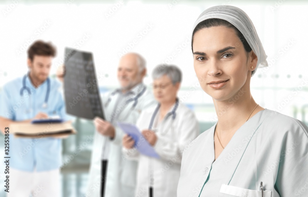 Mid-adult nurse with medical team in background Mid-adult nurse with medical team in background