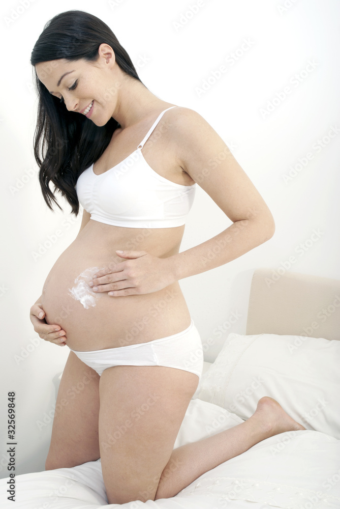 Pregnant woman applying moisturiser to tummy Pregnant woman applying moisturiser to tummy