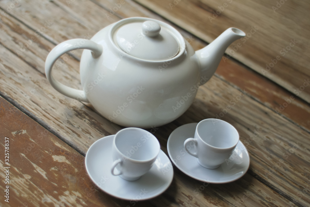 Traditional teapot and two cups set on a wooden table Traditional teapot and two cups set on a wooden table