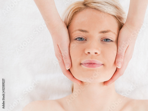 Smiling blond-haired woman getting a massage on her face
