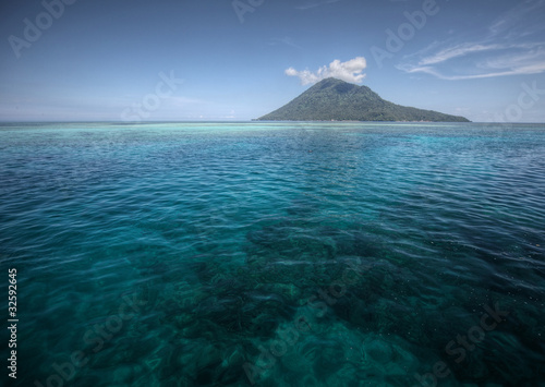 Coral reef transparent sea and white clouds. Bunaken island. Indonesia