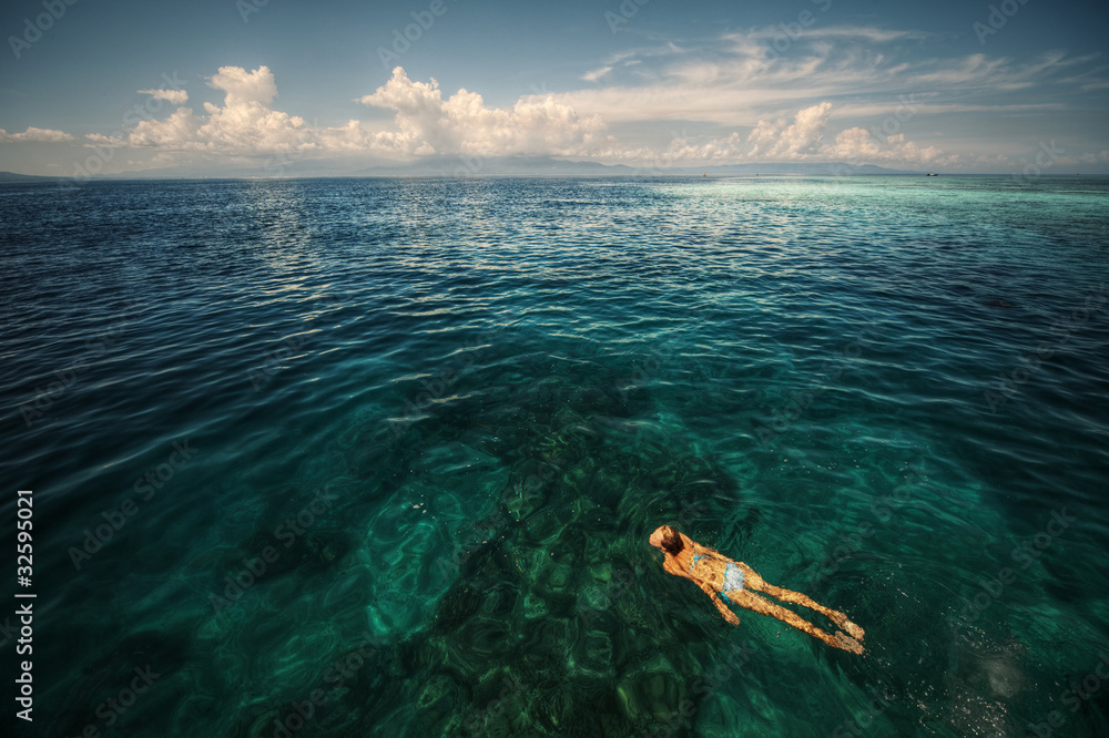 Obraz premium Young woman snorkeling over a coral reef in the transparent tropical sea. Bunaken island. Indonesia