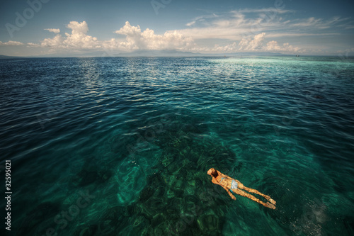 Young woman snorkeling over a coral reef in the transparent tropical sea. Bunaken island. Indonesia