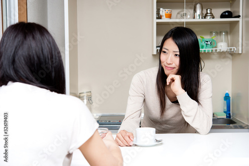 beautiful asian women talking in the kitchen