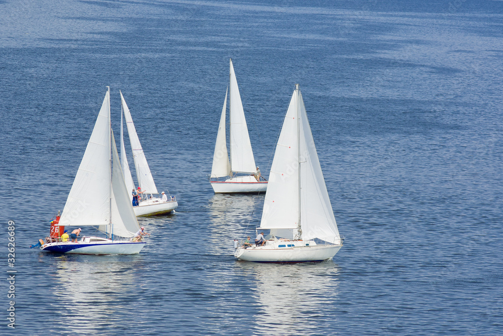Four yachts making a close turn near buoy on a summer river.