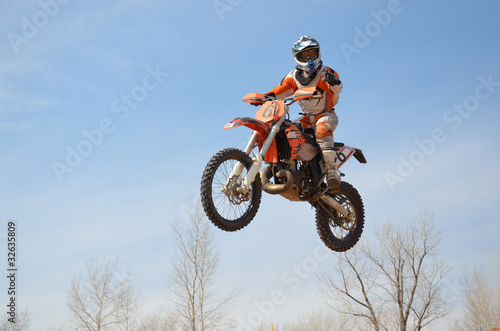 Motocross rider on the motorbike takes off his head turned