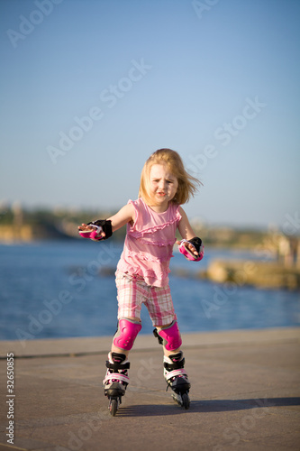 Young pretty girl on rollerskates in the park