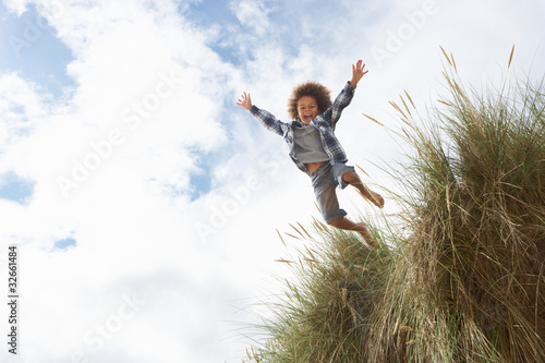 Boy jumping over dune