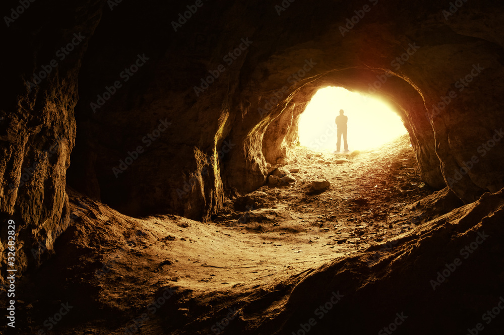 Naklejka premium człowiek stojący przed wejściem do jaskini