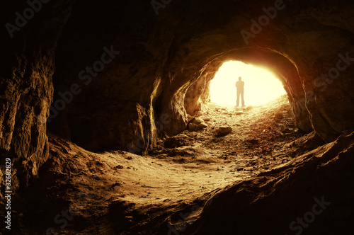 Fotografiet man standing in front of a cave entrance