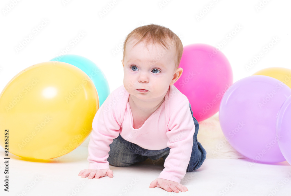 eight-monthly girl in pink jacket  with multi-colored balloons.