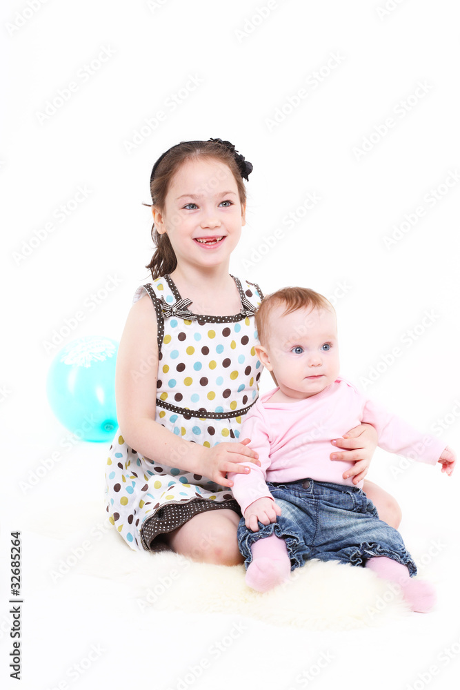 Two sisters sit together. A white background, it is isolated. Two sisters sit together. A white background, it is isolated.