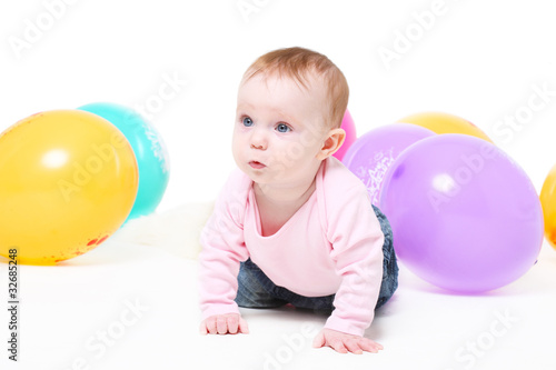 girl in  pink jacket and jeans with multi-colored balloons.
