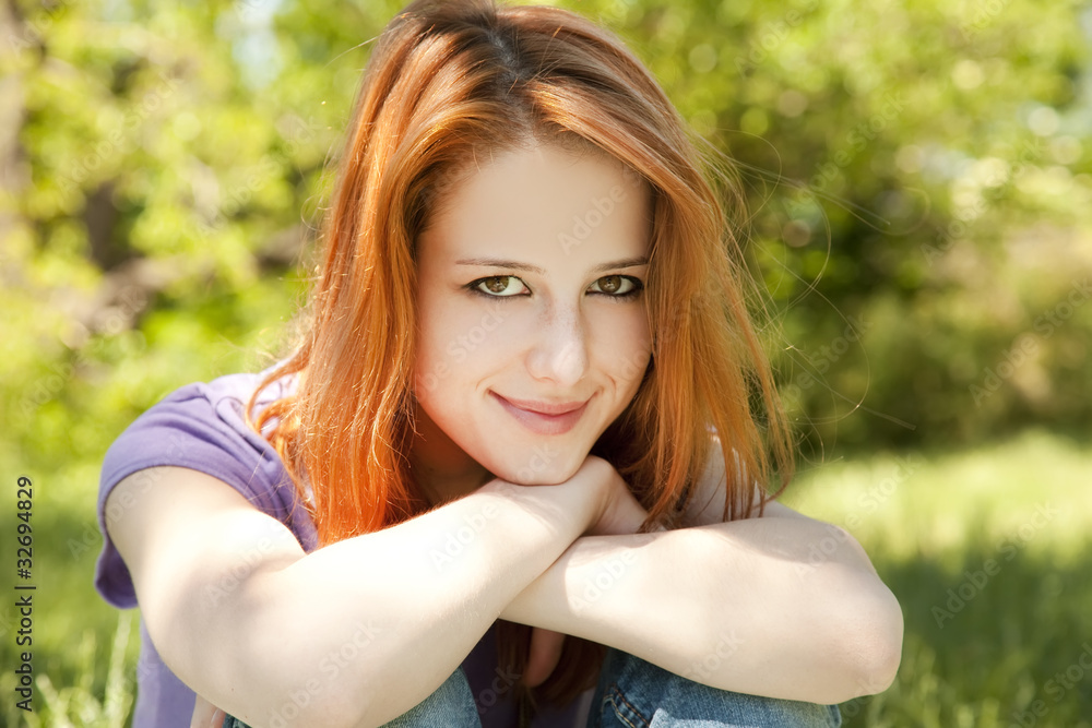 Naklejka premium Beautiful redhead girl at the park in summer time.