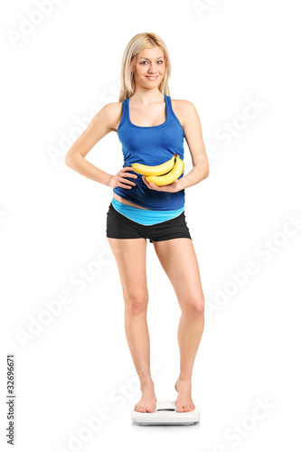 Female athlete on a weight scale holding bananas