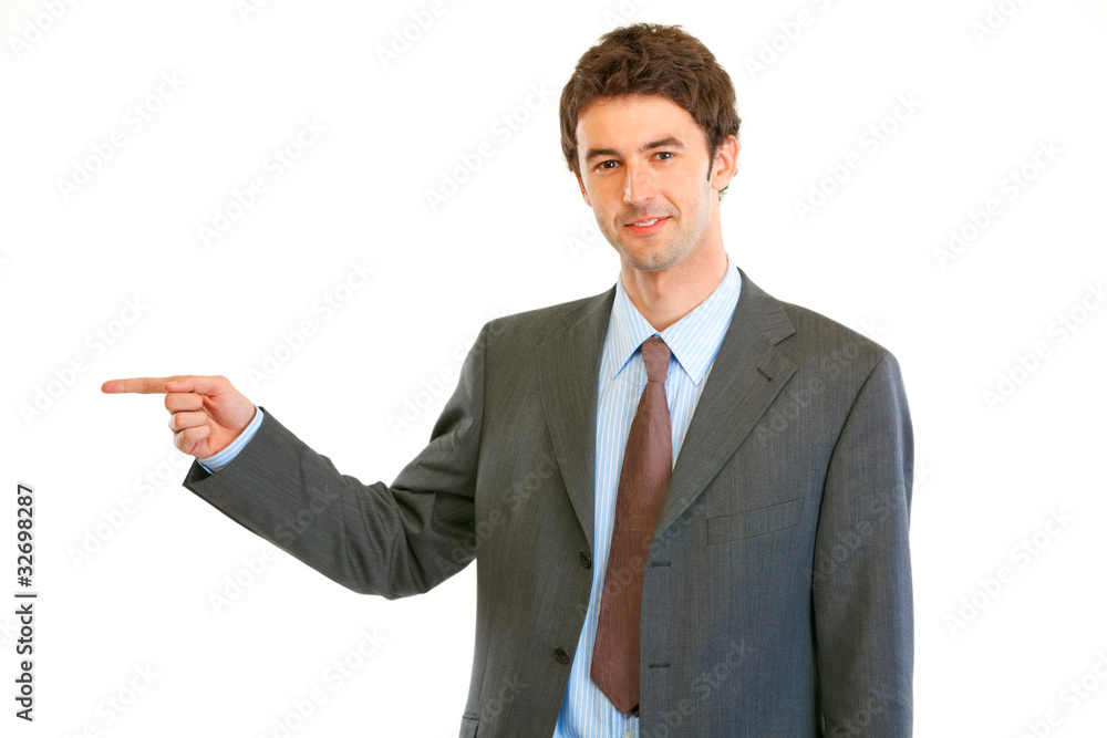 Smiling modern businessman pointing finger at copy space