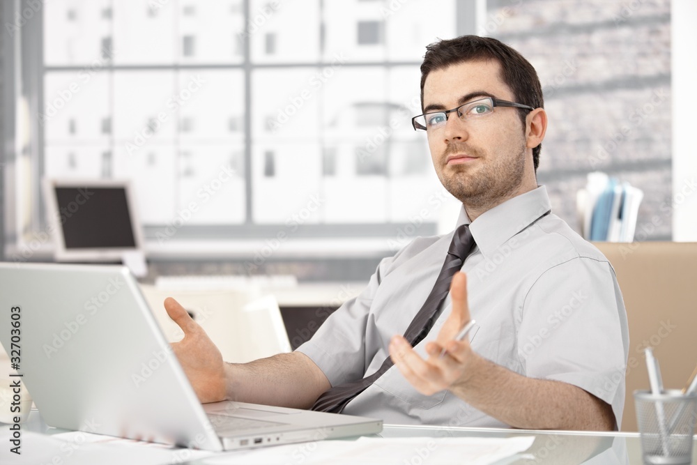 Young stock broker using laptop gesturing Young stock broker using laptop gesturing