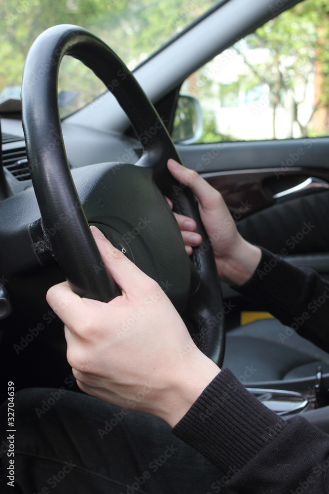 Close-up of male hands on steering wheel in a modern car