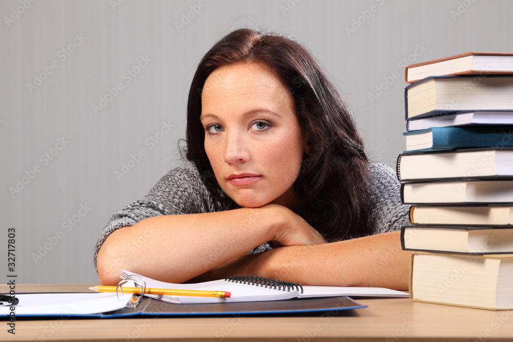 Tired from homework woman rests chin on desk Tired from homework woman rests chin on desk