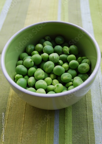 Shelled fresh ripe sweet green peas in a ceramic bowl