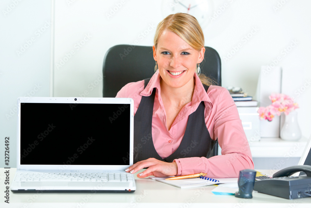 Smiling business woman showing laptop with blank screen. Smiling business woman showing laptop with blank screen.