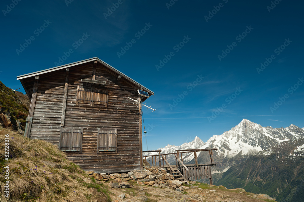 Mountain refuge house in French Alps under blue sky.