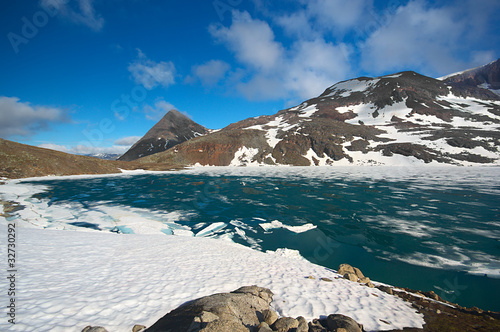 Lake covered by ice, surrounded by snowfields in Northern Norway photo