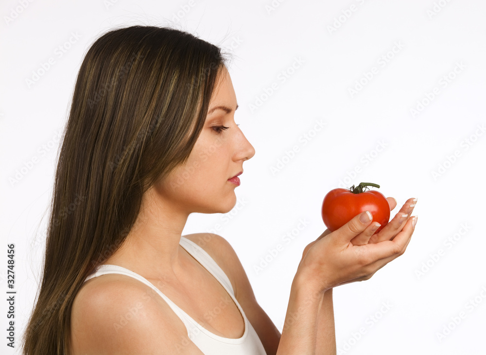 Young woman looking at a fresh tomato in her hands Young woman looking at a fresh tomato in her hands