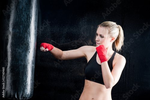 Boxing training woman punching bag in gym