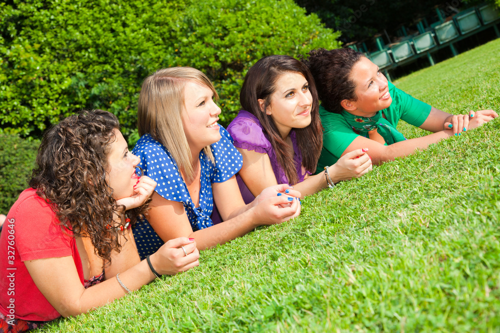 Fototapeta premium Teenage Female Friends Lying on Green at Park