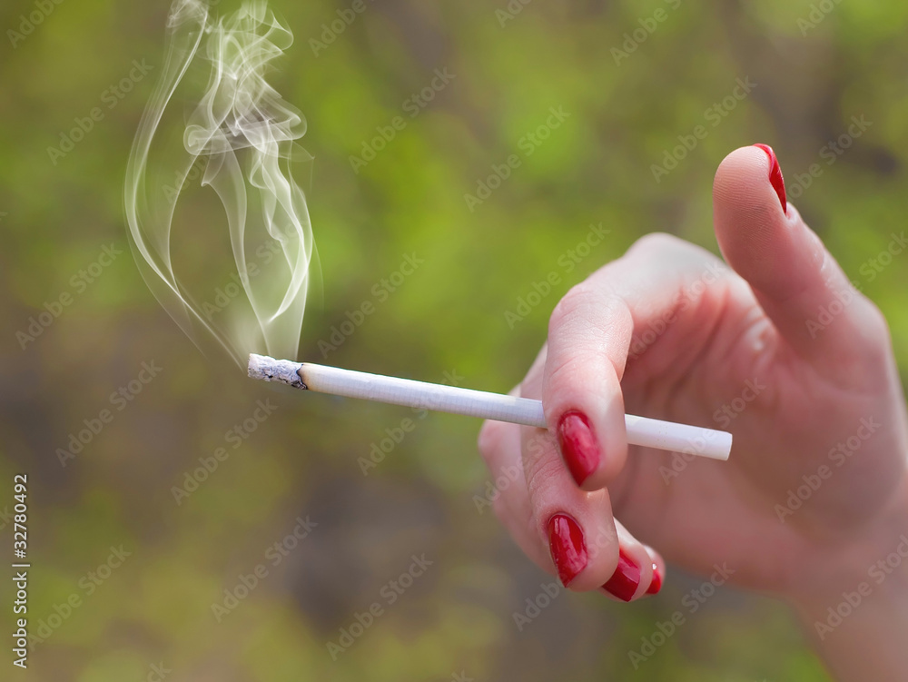 Image of cigarette is in the hand of woman. Image of cigarette is in the hand of woman.