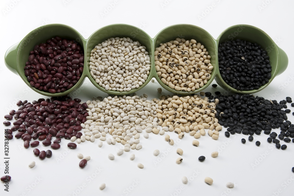 Assorted mixed dried beans spilling in green ceramic dish Assorted mixed dried beans spilling in green ceramic dish
