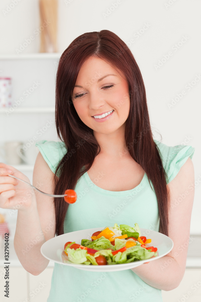 Gorgeous red-haired woman enjoying a mixed salad in the kitchen Gorgeous red-haired woman enjoying a mixed salad in the kitchen