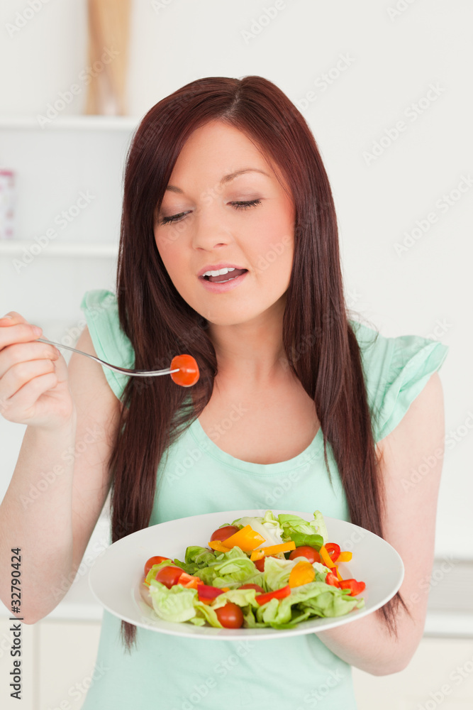 Pretty red-haired woman enjoying a mixed salad in the kitchen Pretty red-haired woman enjoying a mixed salad in the kitchen