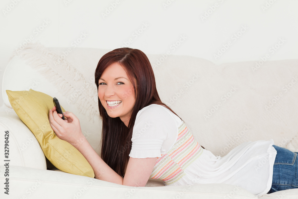 Attractive red-haired female writing a text on her phone while l Attractive red-haired female writing a text on her phone while l