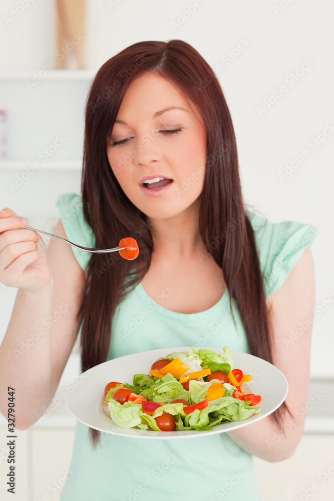 Young red-haired woman enjoying a mixed salad in the kitchen Young red-haired woman enjoying a mixed salad in the kitchen
