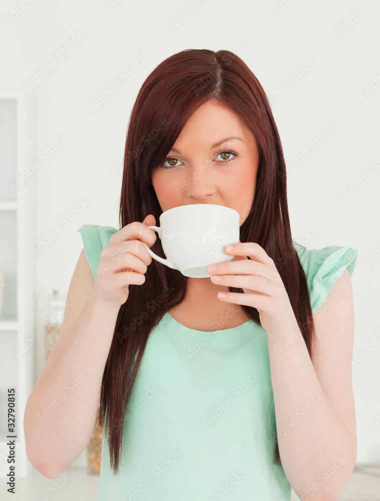 Good looking red-haired woman having her breakfast in the kitche Good looking red-haired woman having her breakfast in the kitche