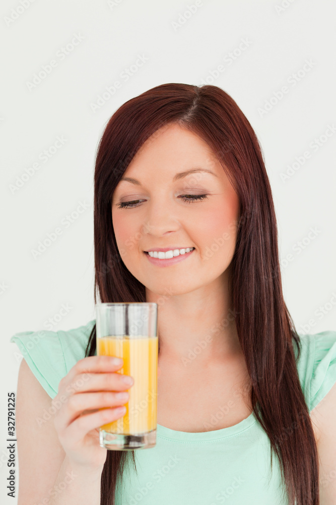 Gorgeous red-haired woman enjoying a glass of orange juice in th Gorgeous red-haired woman enjoying a glass of orange juice in th