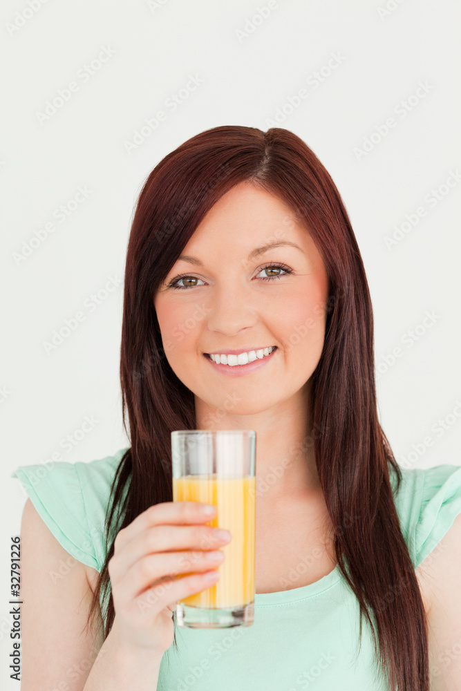 Cheerful red-haired woman enjoying a glass of orange juice in th Cheerful red-haired woman enjoying a glass of orange juice in th