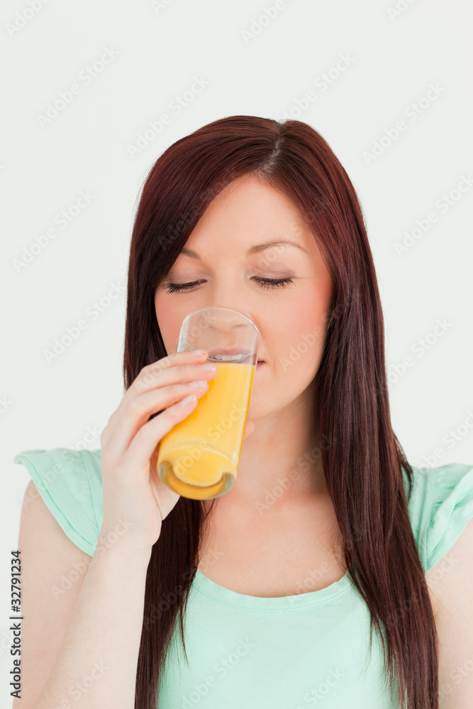 Attractive red-haired woman drinking a glass of orange juice in Attractive red-haired woman drinking a glass of orange juice in