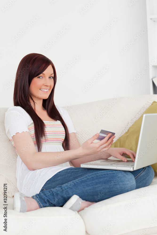 Attractive woman sitting on a sofa is going to make a payment on Attractive woman sitting on a sofa is going to make a payment on