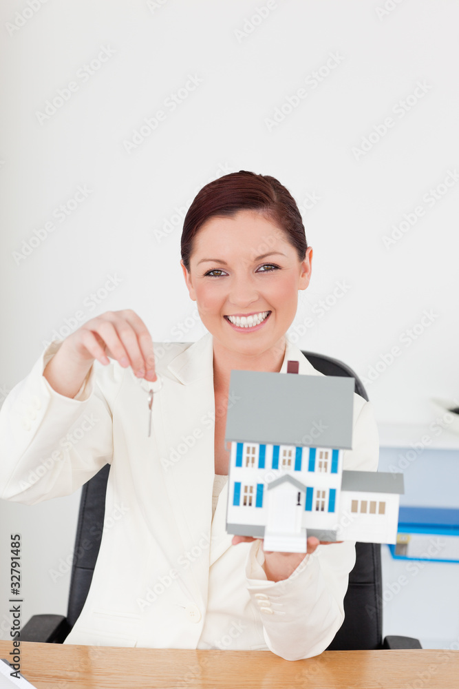 Young pretty red-haired woman in suit holding a blue miniature h Young pretty red-haired woman in suit holding a blue miniature h