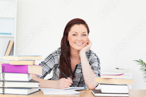 Good looking joyful red-haired girl studying for an examination