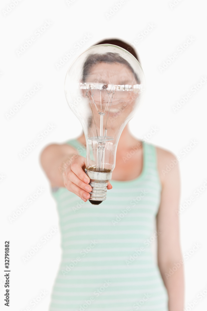 Pretty red-haired female holding a light bulb house while standi Pretty red-haired female holding a light bulb house while standi
