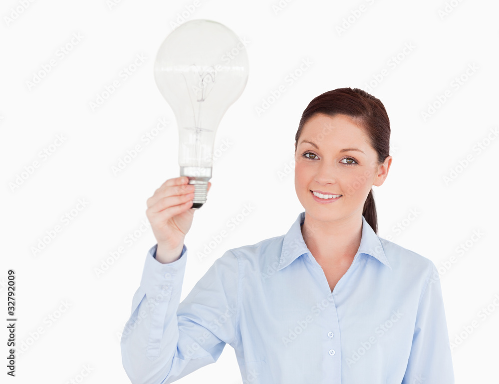 Attractive red-haired woman holding a bulb while standing