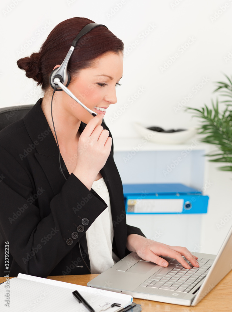 Young beautiful red-haired woman in suit typing on her laptop an Young beautiful red-haired woman in suit typing on her laptop an
